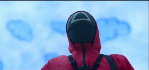 A gif from the show "Squid Game", one of the guards with the mask and a gun